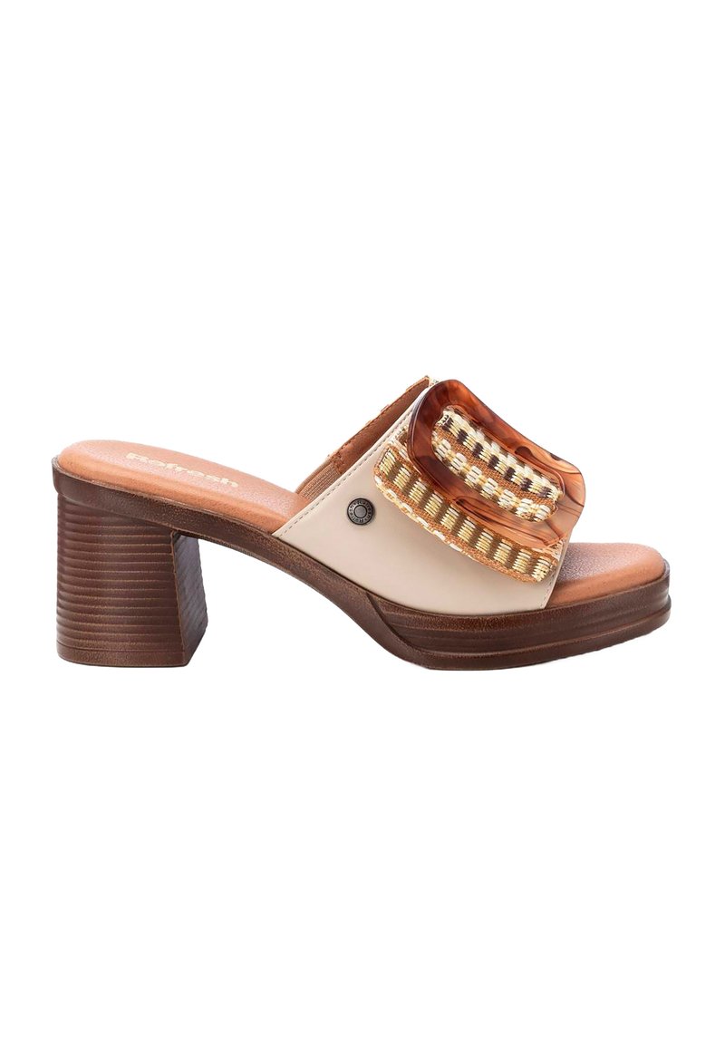 Mules beige de punta abierta con parte superior transparente, acentos de cinta dorada y un tacón grueso marrón. La suela está texturizada para proporcionar agarre.