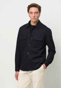 Marine knoopshirt gemaakt van een gestructureerde stof, met twee borstzakken, een klassieke kraag en een gebogen zoom.
