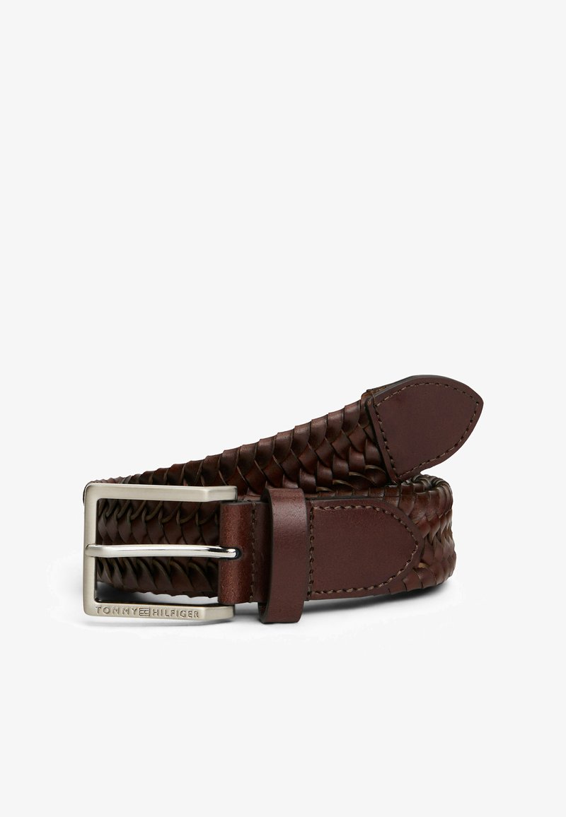 Brązowy pleciony skórzany pasek z metalową klamrą w kolorze srebrnym. Posiada gładkie skórzane wstawki oraz pleciony wzór. Logo marki widoczne na klamrze.