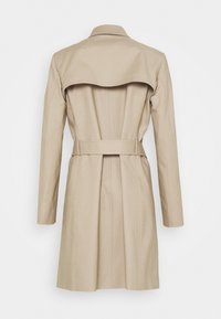Trench-coat beige longueur genou avec manches longues, ceinture à la taille et un empiècement au dos visible de derrière.