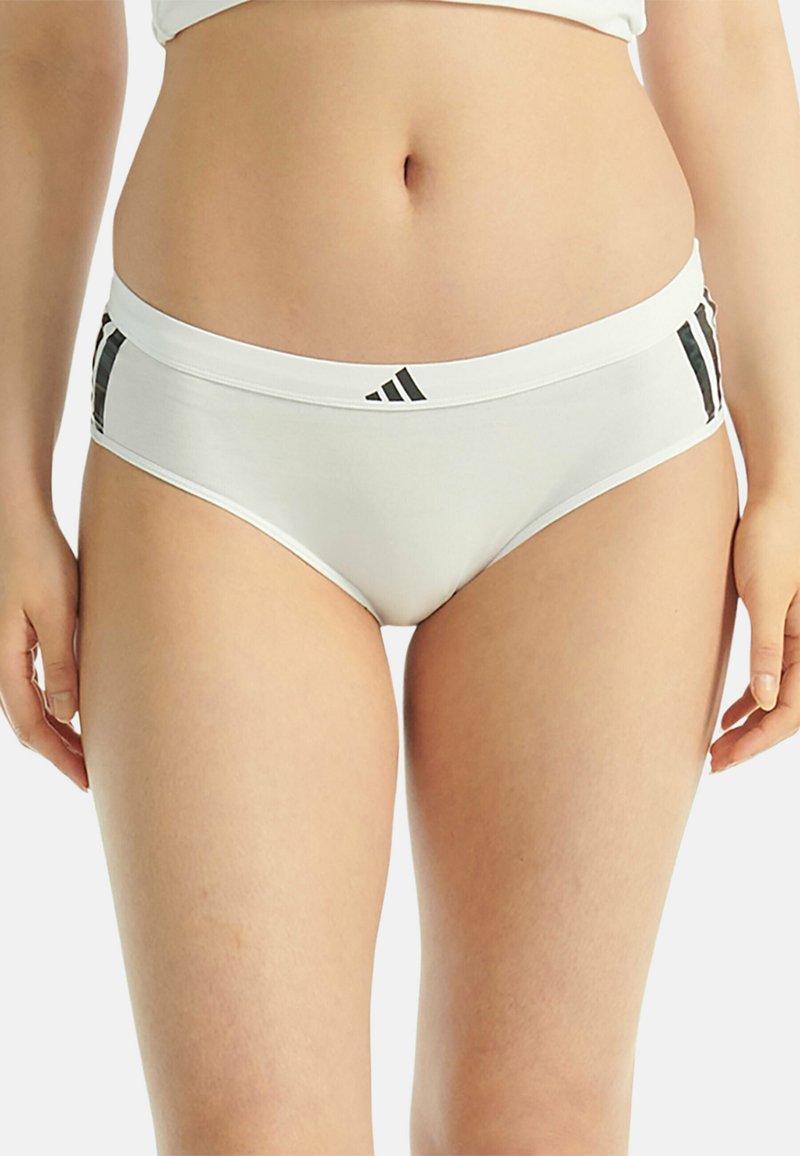 Culottes blanches pour femmes avec une texture douce, présentant un logo noir sur la ceinture et des rayures verticales noires sur les côtés.