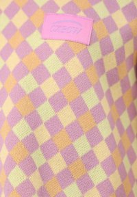 Pull en tricot avec un motif à carreaux multicolore dans les tons rose, jaune et vert. Présente une petite étiquette rose avec "OXBOW" en bleu.