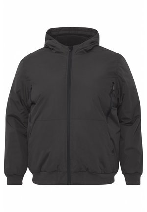 Chaqueta negra con capucha, cierre frontal, puños elásticos, dos bolsillos laterales y acabado de tela suave y mate. Diseño limpio y moderno.