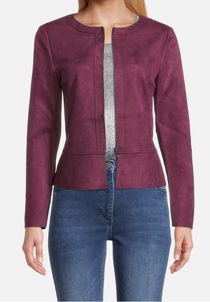 Femme portant une veste violette ajustée, ouverte sur le devant, à manches longues, par-dessus un haut gris clair à motifs et un jean bleu.