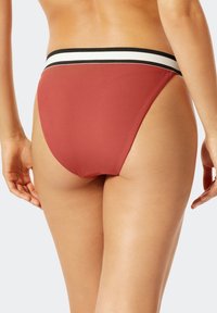 Bikini spodní díl s vysokým pasem v barvě terakota s elastickým páskem s černo-bílými pruhy. Žebrovaná struktura, minimal coverage design.