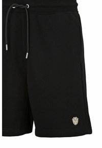 Zwarte fleece shorts met een elastische tailleband, trekkoord, zakken en een klein crèmekleurig embleem op de linker onderkant. Glad stoftextuur.