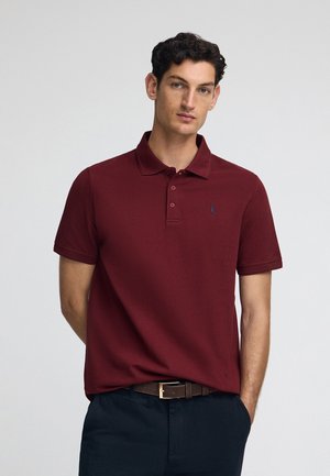 Polo shirt bordeaux en tissu léger, avec un col classique et une patte de boutonnage à trois boutons, arborant un petit logo brodé sur la poitrine.