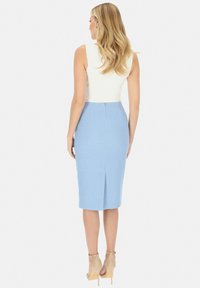 Jasnoniebieska spódnica ołówkowa z fakturowym wykończeniem, z rozporkiem z tyłu i ukrytym zapięciem. Połączona z dopasowaną białą bluzką.