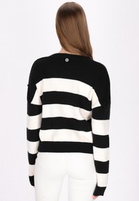 Maglione a righe bianco e nero con scollatura tonda, spalle cadute e orlo a coste. Presenta un piccolo logo sul retro.