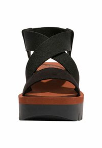 Černé platformové sandály s křížovými textilními popruhy, s polstrovanou stélkou v červenohnědé barvě a texturovanou černou gumovou podrážkou.