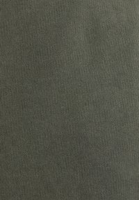 Gros plan d'un tissu vert olive tissé serré avec une texture côtelée fine et des lignes verticales régulières.