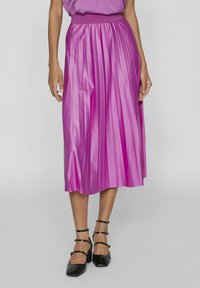 Plisserad midiklänning i klar rosa satin med elastisk midja. Matchad med svarta klackar med fyrkantig tå och ankelsnören.