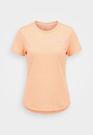 Maglietta sportiva Nike Dri-FIT a maniche corte color pesca, con scollo rotondo e piccolo logo riflettente sul petto sinistro.