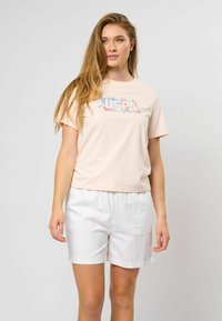 Lys rosa bomull t-skjorte med et fargerikt "USPA" blomsterdesign. Kombinert med hvite shorts, som viser en avslappet passform og en uformell stil.