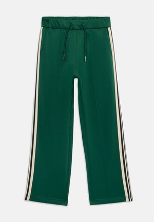 Grüne Sporthose mit elastischem Bund, Kordelzug und zwei seitlichen Taschen. Mit kontrastierenden cremefarbenen und schwarzen Streifen an den Seiten.