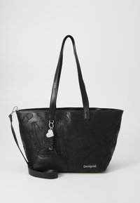 Bolso tote de cuero negro con un diseño floral en relieve, asas dobles, correa de hombro desmontable y un charm plateado. Logo de la marca exhibido de forma prominente.