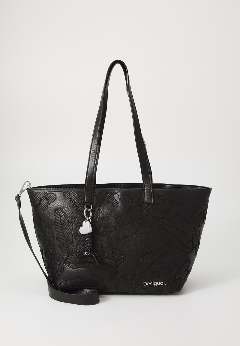 Bolso tote de cuero negro con un diseño floral en relieve, asas dobles, correa de hombro desmontable y un charm plateado. Logo de la marca exhibido de forma prominente.