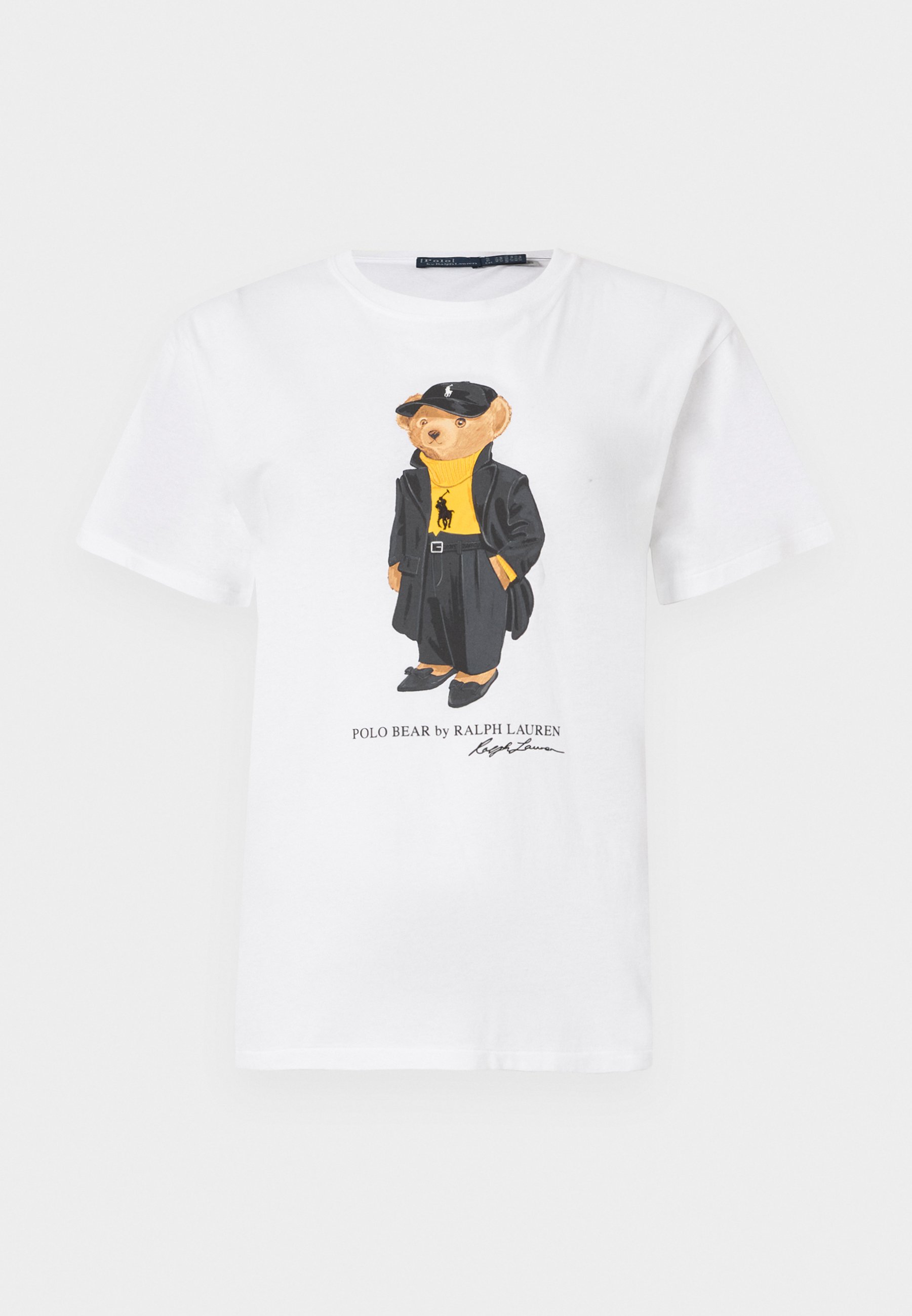Bela bomba majica iz bombaža s karikaturnim medvedom v črnem plašču in kapici, rumenim puloverjem in črnimi čevlji. Vključen je napis "Polo Bear by Ralph Lauren."