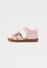 Rosa lädersandal med blomaccent, öppen tå-design, justerbar rem och brun gummisula. Platt, avslappnad stil för barn.