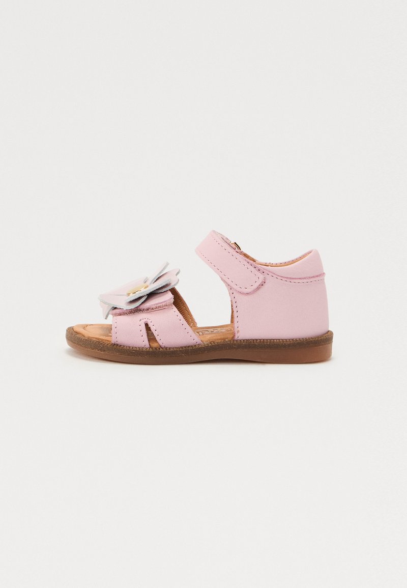 Rosa lädersandal med blomaccent, öppen tå-design, justerbar rem och brun gummisula. Platt, avslappnad stil för barn.