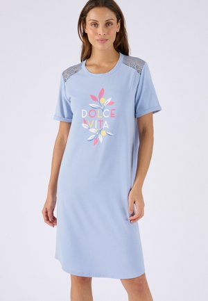 Vrouw draagt een lichtblauwe knielange jurk met kanten schouderaccenten en de tekst "Dolce Vita" met kleurrijke bladeren aan de voorkant.