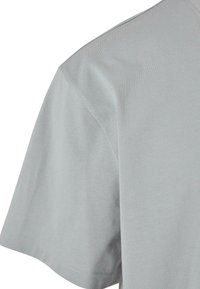 Tricou din bumbac gri deschis, cu mâneci scurte, decolteu rotund și textură fină. Prezintă cusături minime pe margini.
