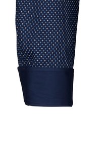 Manica di camicia blu navy con piccoli motivi a rombi blu chiaro e bianchi e un polsino blu navy uniforme.