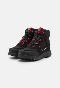 Scarpe da trekking nere con accenti rossi, dotate di una tomaia testurizzata, colletto imbottito e suola in gomma resistente con un motivo di battistrada grip.