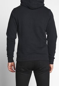 Felpa nera con cappuccio, dal design morbido, con polsini e orlo a costine, e una vestibilità classica, vista da dietro.