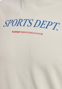 Lys beige bomuld T-shirt med blå "SPORTS DEPT." tekst og rød "hummel PERFORMANCE" logo. Glat tekstur, standard crew neck design.