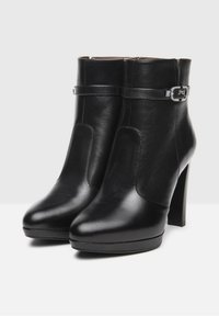 Black leather ankle boots with a smooth finish, pointed toe, and high heel. Features a strap with a metal buckle accent.