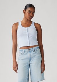 Heledad siniste rib bermuda-särgid, mille keskel on nupud, koos heledate siniste denim lühikeste pükstega. Sile tekstuur, juhuslik sobivus, ilma varrukateta disain.
