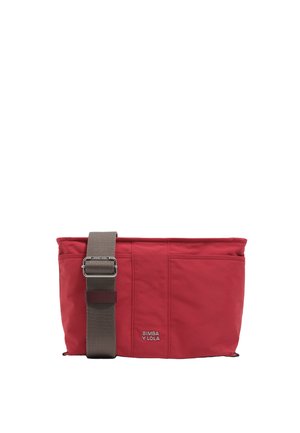 Bolso de hombro de tela roja con una correa ajustable marrón, que presenta costuras visibles y un detalle de logo en el frente. Forma rectangular.