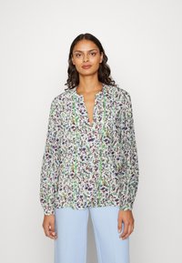 Blusa a fantasia floreale con maniche lunghe e scollatura a V. Presenta dettagli in verde e un tessuto leggero e testurizzato.