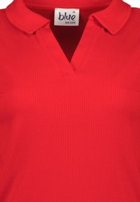 Punainen polo-paita, jossa on ribbed-textuuria ja kaulus, V-mallinen muotoilu. Tunnuksessa lukee "blue seven" ja koko 36.