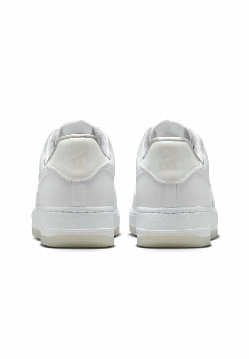 Witte leren Nike Air sneakers met rubberen zolen, gevoerde kraagjes en geperst merklogo op de hiel, met een gladde, gestructureerde afwerking.