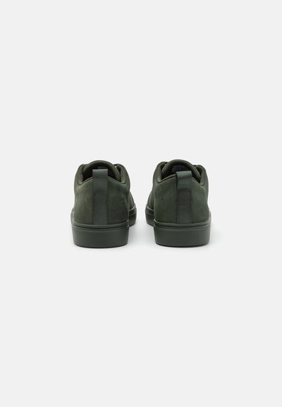 Dark green suede sneakers with a smooth finish, rounded shape, rear pull-tab, and a contrasting rubber sole.