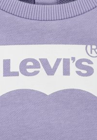 Lila sweatshirt med en djärv vit Levi's-logotyp och en böjd grafisk design i botten. Slät yta med ribbad halsringning.