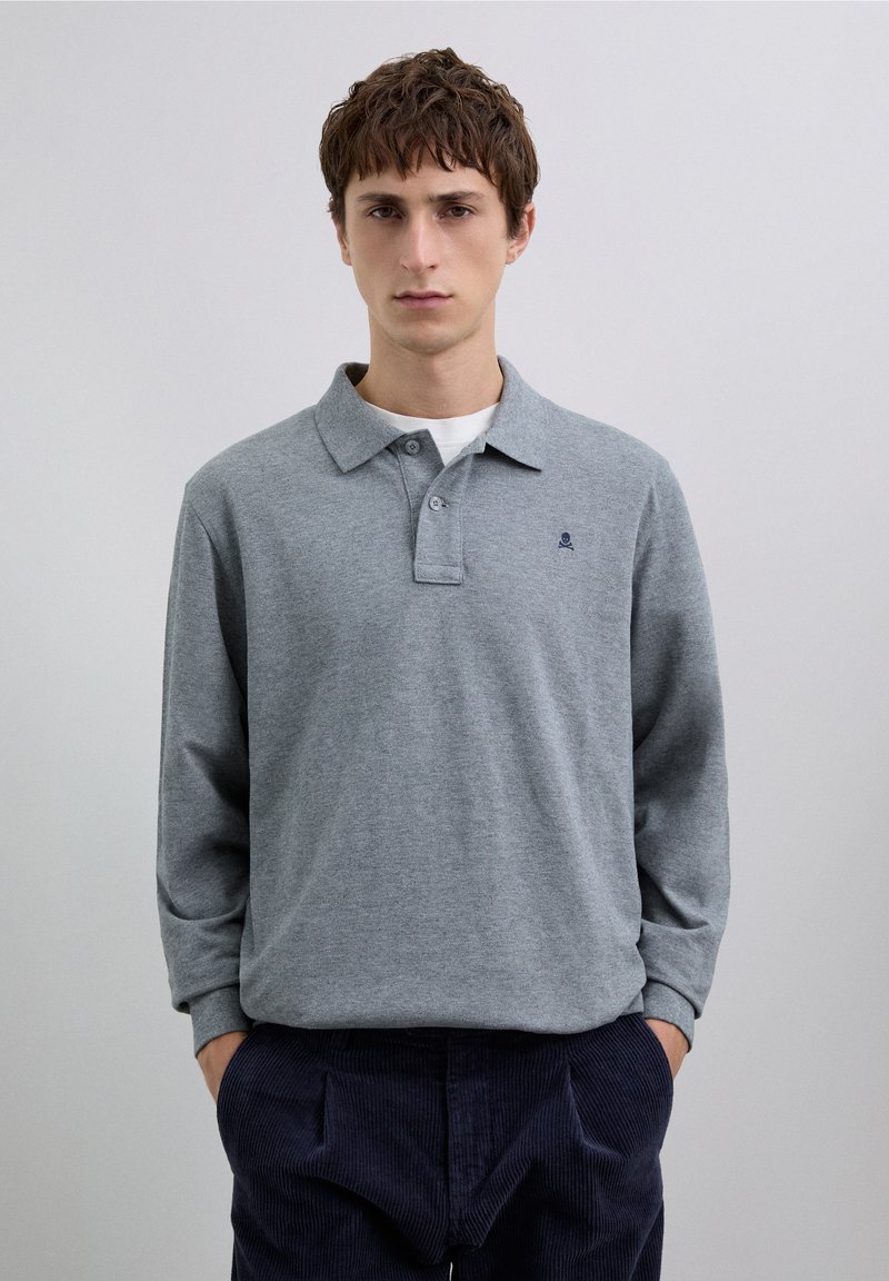 Polo à manches longues gris avec un col à revers et une patte de boutonnage à bouton unique. Comprend un petit logo sombre sur le côté gauche de la poitrine.