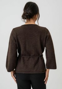 Brauner, gestrickter Pullover mit langen, weiten Ärmeln, einem taillierten Bund und einem runden Halsausschnitt. Glatte Textur mit einem dezenten melierten Muster.