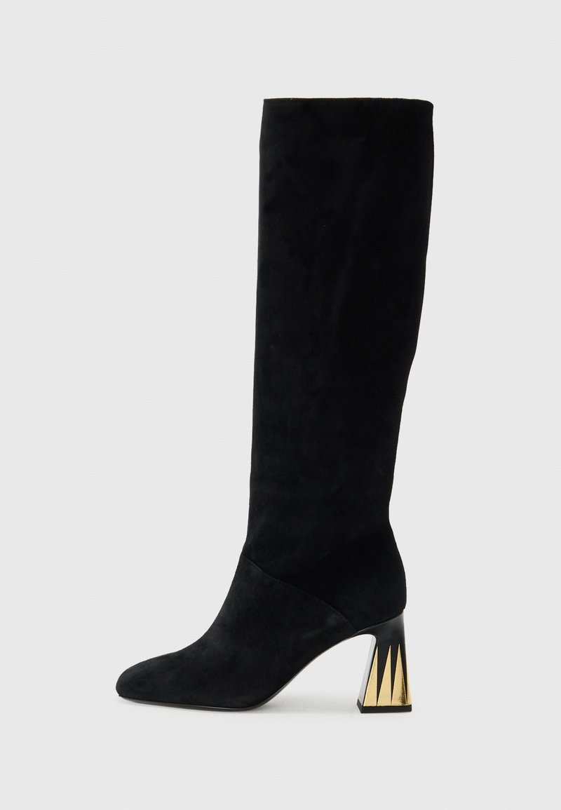 Schwarze Wildleder-Stiefel bis zum Knie mit spitzer Zehenform und Blockabsatz, die goldene dreieckige Akzente auf einem schlichten Hintergrund zeigen.