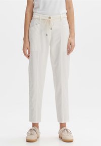 Witte katoenen broek in een katoenmix met een koordje in de taille, zijzakken, een taps toelopend ontwerp en een gemêleerde stof, gecombineerd met lichtgekleurde sneakers.