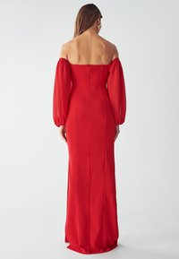 Czerwona wieczorowa sukienka off-shoulder z bufkami, zamek błyskawiczny z tyłu, dopasowany fason oraz zwiewny krój długości do ziemi.