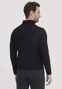 Marineblauer Pullover mit hohem Kragen und taillierter Passform. Aus einem weichen, strukturierten Stoff gefertigt. Minimalistischer Stil mit geripptem Saum und Bündchen.