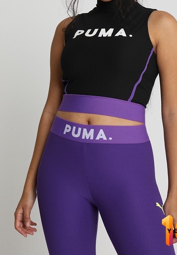 Czarny prążkowany crop top z białym logo "PUMA"; fioletowe legginsy z wysokim stanem o prążkowanej fakturze oraz logo na tyle i z boku.