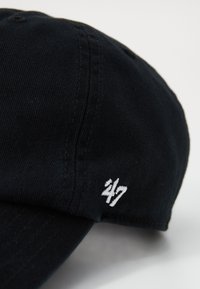 Schwarze Baseballmütze aus Baumwolltwill, mit einem gebogenen Schirm und aufgesticktem weißen "24/7"-Logo an der Seite. Strukturierter Stoff.