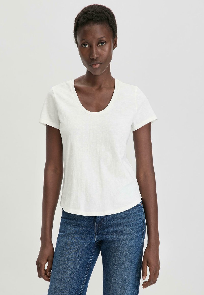 T-shirt bianco a maniche corte con scollatura rotonda e vestibilità comoda, realizzato in tessuto morbido, abbinato a jeans blu.