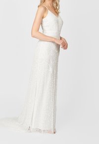 Biała suknia wieczorowa na cienkich ramiączkach, ozdobiona misterną koralikową aplikacją, z dopasowanym gorsetem i płynącą sylwetką.