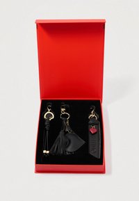 Μαύρο δερμάτινο σετ μπρελόκ σε κόκκινο κουτί, με φούντα, κομμάτι σε σχήμα καρδιάς και λουράκι με την επιγραφή "VALENTINO" σε χρυσό.
