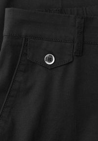 Gros plan sur une poche de pantalon noire avec rabat fermé par un bouton argenté et passant de ceinture visible en haut à droite.